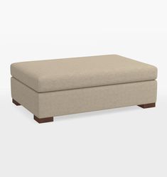 a beige ottoman sitting on top of a white floor next to a wooden leg rest