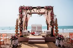 an outdoor ceremony set up on the beach with chairs and flowers in front of it