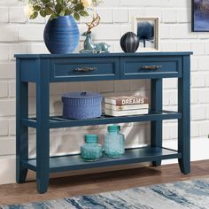 a blue table with two drawers and some vases on the shelf next to it