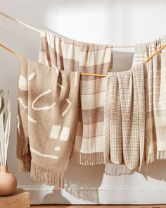 some towels hanging on a clothes line next to a potted plant and a vase