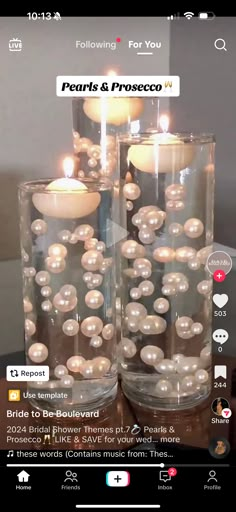 two vases filled with pearls and candles on top of a wooden table next to each other