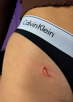 a woman's stomach with a small red chili tattoo on her left side belly