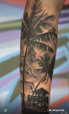 a man's arm with a palm tree and house on the beach in front of it