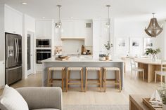 a kitchen with white cabinets and an island in front of the stove, refrigerator and microwave