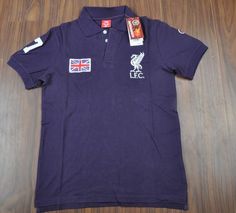 the polo shirt is purple with white and red logos on it, sitting on a wooden floor