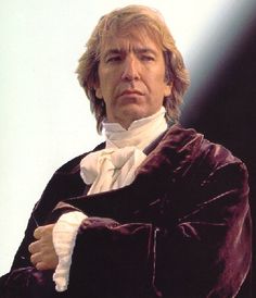 a man with long hair wearing a black coat