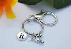 a silver keychain with the letter r on it and a bird charm attached to it