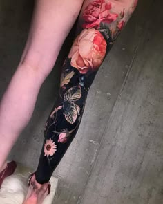 a woman's leg with flowers and butterflies on it, next to a white dog