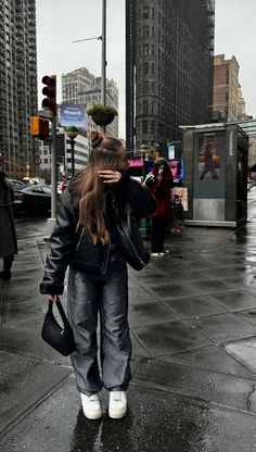 a woman is walking down the street talking on her cell phone