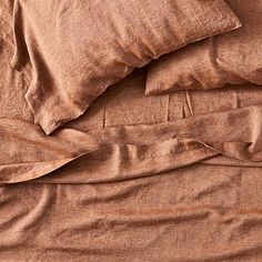 an unmade bed with brown sheets and pillows