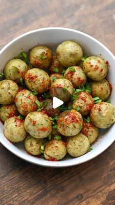 a white bowl filled with small balls of food on top of a wooden table next to a knife