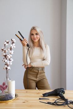 a woman holding a hair dryer while sitting at a table