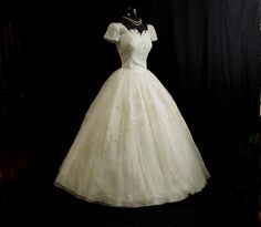 a white wedding dress on display in a dark room