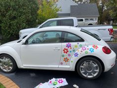 a white car with flowers painted on it's side parked in a parking lot