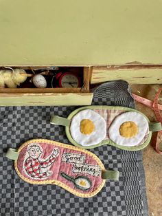 two fried eggs are sitting on top of a checkered table cloth with an egg patch in the middle