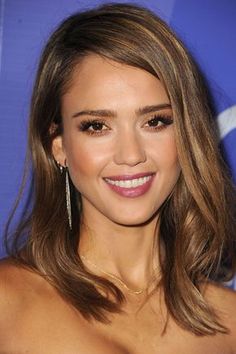 a close up of a person with long hair wearing earrings and smiling at the camera