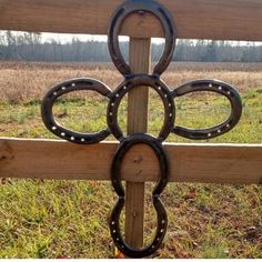 a wooden fence with an iron ring on it's side in front of a field