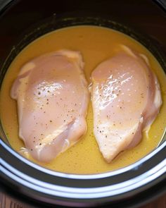 two pieces of chicken in a sauce in a slow cooker