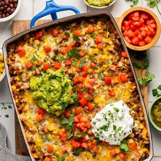 an enchilada casserole in a baking dish with sour cream on top