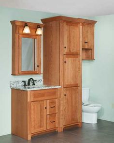 a bathroom with wooden cabinets and marble counter tops, along with a white toilet in the background