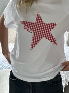 a woman wearing a white shirt with a red gingham star on it