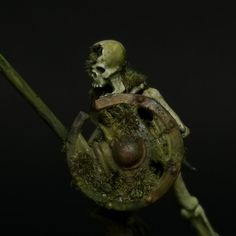 a creepy looking figure holding onto a piece of wood with moss growing on it's back