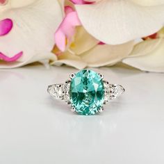 an oval cut blue and white topaz ring with diamond accents on the sides, surrounded by flowers