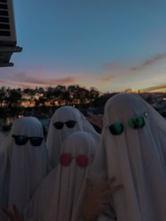 several people dressed in white with sunglasses on their heads and one person holding up her hand