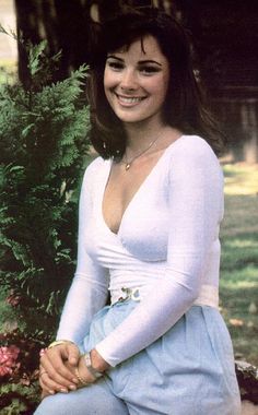 a woman sitting in front of a bush smiling