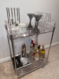 a bar cart with wine glasses, liquor bottles and other condiments on it