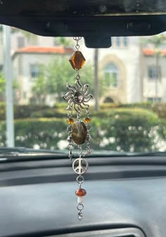 a car dashboard with a sun catcher hanging from it's center console, decorated with beads and charms