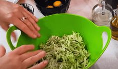 two hands are sprinkling shredded broccoli in a green bowl on the kitchen counter