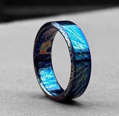 a ring with blue and gold inlays on the inside, sitting on concrete