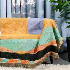 a colorful blanket sitting on top of a chair next to a potted plant