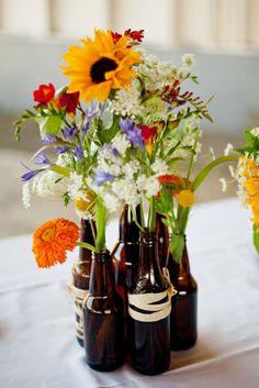 several brown bottles with flowers in them on a table