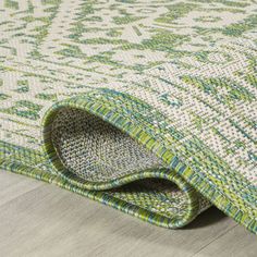 a green and white rug on the floor with a wooden floor in front of it