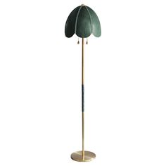 a green and gold floor lamp with an umbrella shaped shade on it's base