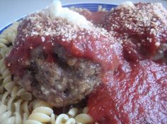 two meatballs covered in sauce and pasta on a plate