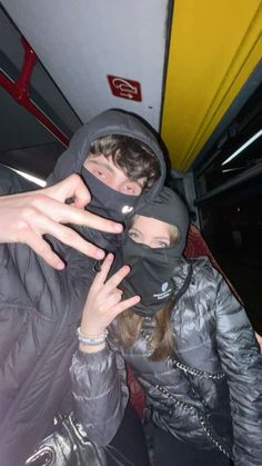 two people standing on a bus with their hands in the air and one person wearing a face mask