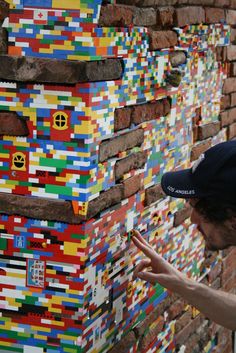 a man pointing at a wall made out of legos