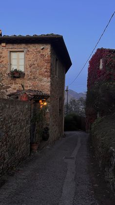 an alley way with stone buildings and flowers on the side, at dusk in italy