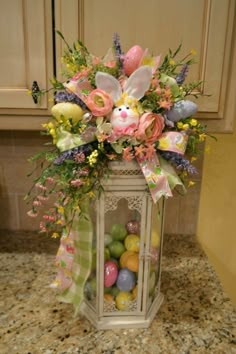 a white lantern filled with lots of flowers and easter eggs on top of a counter