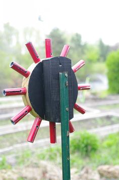 a red and black object on top of a green pole in front of some grass