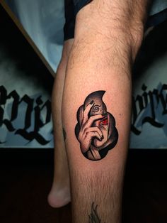 a man's leg with a black and grey tattoo on it, holding a red eye