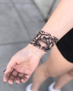 a woman's hand with a black and white tattoo design on the left wrist