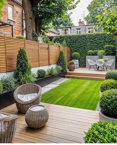 an outdoor garden with wooden decking, grass and potted plants