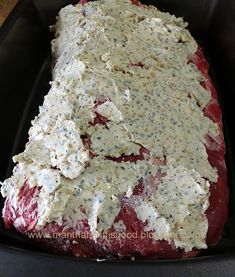 a large piece of meat covered in cheese on top of a black pan with a wooden table