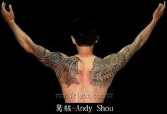 the back of a man with tattoos on his body and wings above his head, in front of a black background