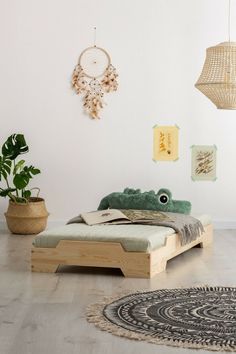 a bed sitting on top of a wooden floor next to a potted plant