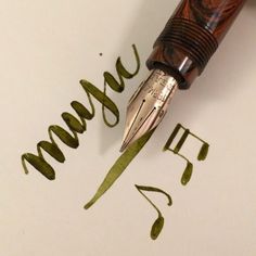 a fountain pen writing the word march on paper with green ink and some type of cursive